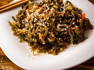 Seaweed salad with sesame seeds is on a white plate