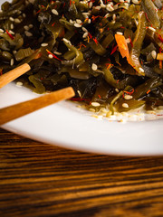 Seaweed salad with sesame seeds is on a white plate