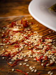 rosemary and sesame spices near white plate on wooden background.