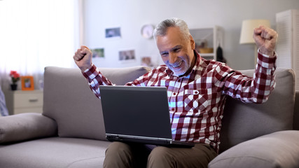 Cheerful elderly man getting answer on dating site, receiving good news, luck