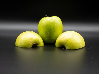 Fototapeta na wymiar green apples cut in half on black background