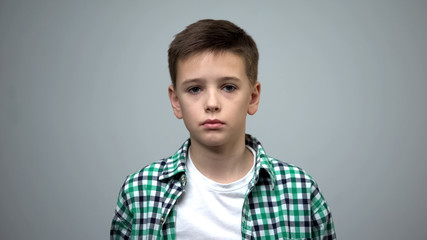 Little pale boy sadly looking into camera, victim of bullying, orphanage