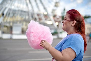 Young and fat woman holding cotton candy in hand