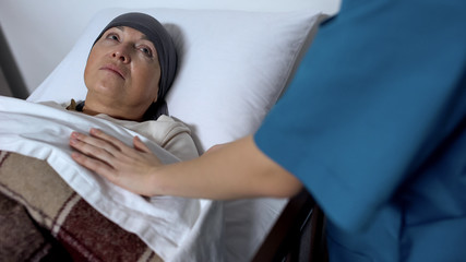 Sick-nurse covering senior patient with blanket, suffering cancer, support