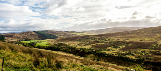 A scenic colourful landscape of a small valley surrounded by small hills in Cairngorms National park, Scotland