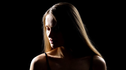 Beautiful young lady turning face to camera against black background, femininity