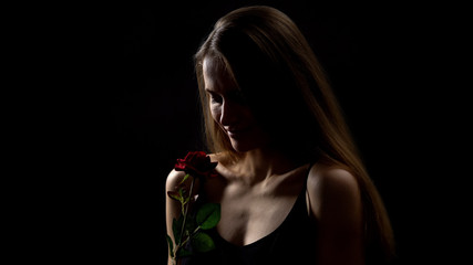 Smiling woman holding red rose, romantic symbol and femininity, Valentines day