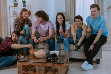 Portrait of a very charismatic people cheers with beer bottles in front of the tv while watching the football match very excited waiting to see all match tv