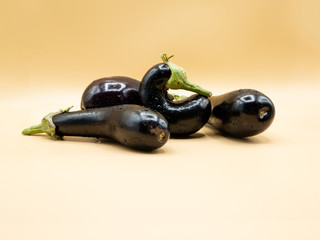 four aubergines or eggplants on beige background