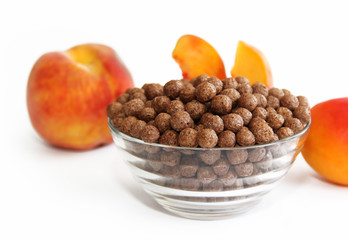 sweet chocolate corn balls in glass plate and peach on a white background