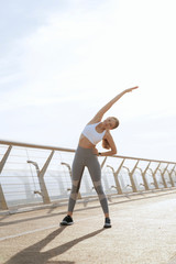 Smiling athletic lady doing side body bending
