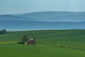 Fototapeta na wymiar Rural abstract landscape with rolling hills and windmill in South Moravia, Czech Republic