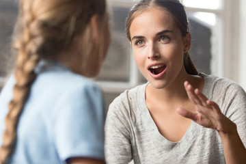 Young mother talking with daughter emotionally gesticulating using sign language