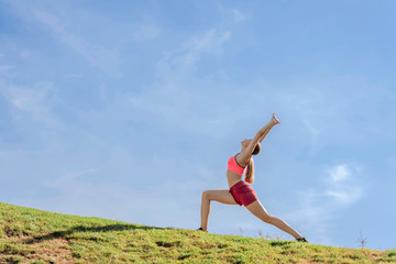 Fototapeta na wymiar Young lady doing yoga practice on green hill