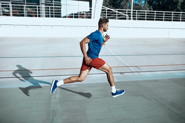 Fototapeta premium Sportive man running on stadium in city