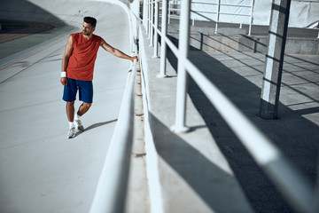 Adult sportsman standing near fence, preparing to training in city