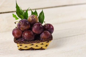 basket with plums on a light background, healthy concept