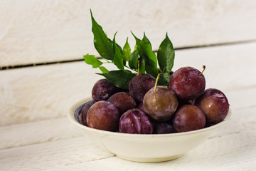 plate with plums on a light background, healthy concept