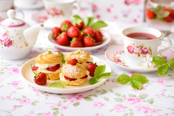 Profiteroles with strawberries on the summer table