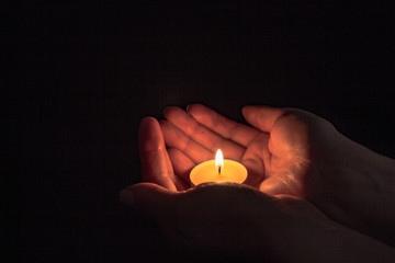 round candle in female hands, light in hands, festive theme