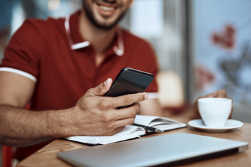 Obraz premium Young man is using smartphone in cafe