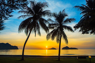 Obraz na płótnie Canvas Sunrise at sea with islands and coconut trees.