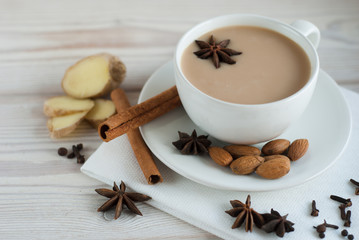 Traditional indian masala tea with spices in a white Cup on a white cloth napkin