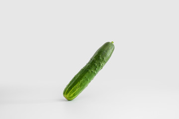 Fresh juicy green cucumber flies on a uniform white light background. Minimal concept, copy space. The idea of healthy eating
