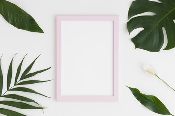 Top view of a pink frame mockup with tropical leaves decoration. Portrait orientation.