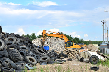 Industrial landfill for recycling used rubber tires and old concrete structures. Excavator with hydraulic shears for crushing and cutting reinforced concrete slabs. Secondary crushed stone - Image