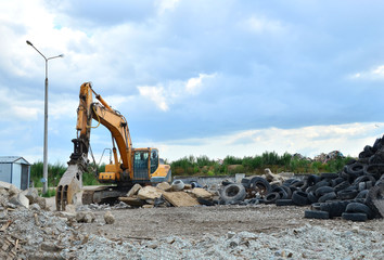 Industrial landfill for recycling used rubber tires and old concrete structures. Excavator with hydraulic shears for crushing and cutting reinforced concrete slabs. Secondary crushed stone - Image