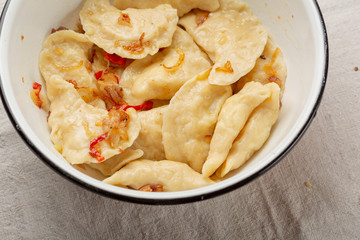 Russian dumplings with potato in white enamel bowl