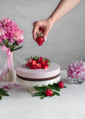 cake on a stand with strawberries in hand