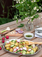 Potato salad on the table in the garden background. healthy food concept. springtime