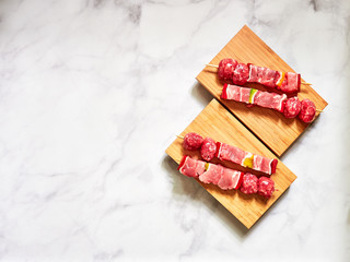 uncooked beef skewers top down view isolated over a wood plank with a dark background