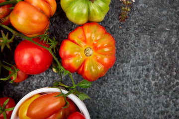 Mix of tomatoes background. Beautiful juicy organic red tomatoes on black  table background. Clean eating concept. Copy space, flat lay..