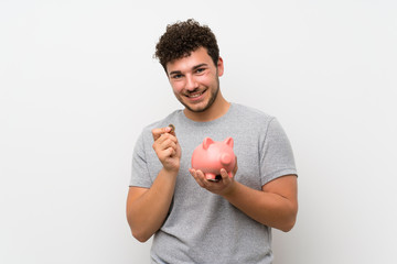 Man with curly hair over isolated wall holding a big piggybank