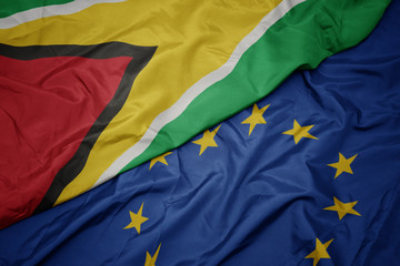 waving colorful flag of european union and flag of guyana.