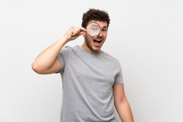 Fototapeta premium Man with curly hair over isolated wall holding a magnifying glass