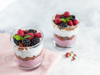 granola in a glass with chia yogurt and fresh berries on a light background