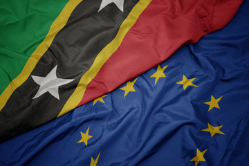 waving colorful flag of european union and flag of saint kitts and nevis.