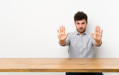 Young man with a table making stop gesture and disappointed