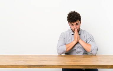 Young man with a table keeps palm together. Person asks for something