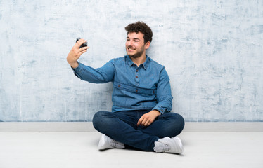 Young man sitting on the floor making a selfie