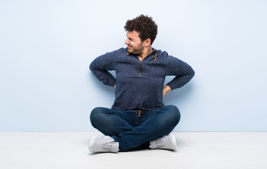 Young man sitting on the floor suffering from backache for having made an effort