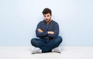Young man sitting on the floor feeling upset