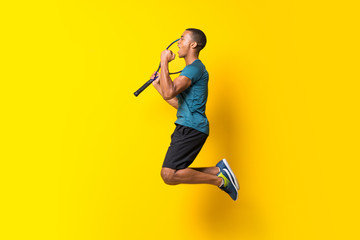 Afro American tennis player man over isolated yellow background