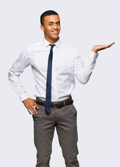 Young afro american businessman holding copyspace imaginary on the palm to insert an ad on isolated background