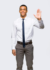 Young afro american businessman saluting with hand with happy expression on isolated background