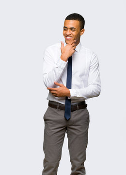 Young afro american businessman looking to the side with the hand on the chin on isolated background